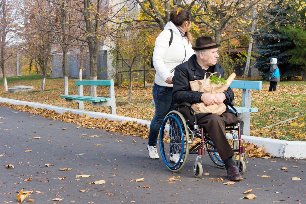 Carer pushing a disabled man in wheelchair